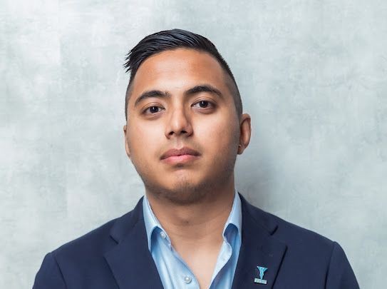 Person in a suit posing against a light gray background.